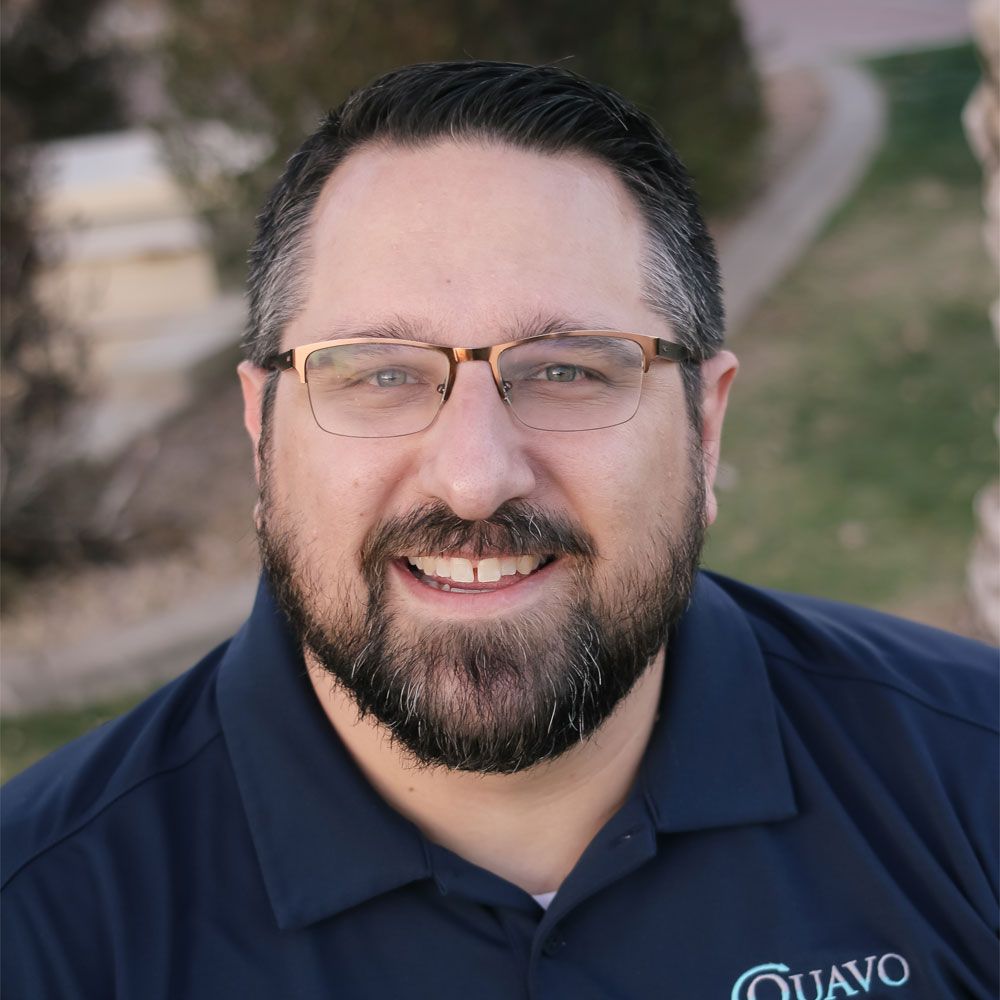 Bearded man wearing glasses smiling outside