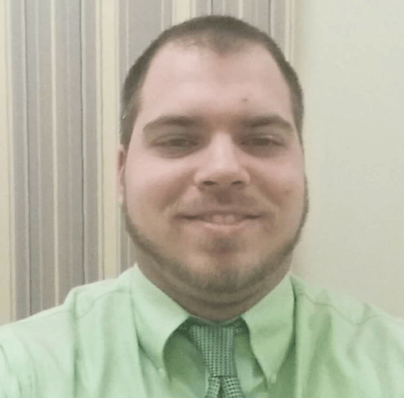 Bearded man smiling wearing a green button up shirt